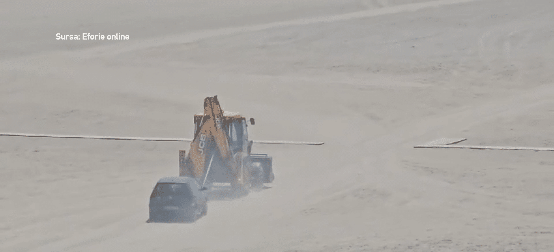 Mașină tractată pe nisip de un excavator