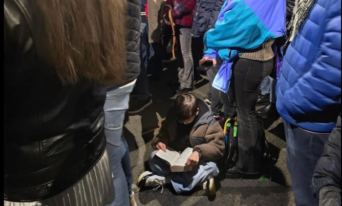 Imaginea serii la protestele din București: un băiețel citește pe asfalt, în timp ce mama îi luminează cartea cu telefonul. „România încă are speranță”